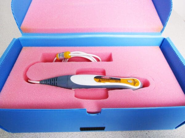 A pair of scissors in a box with a cord.