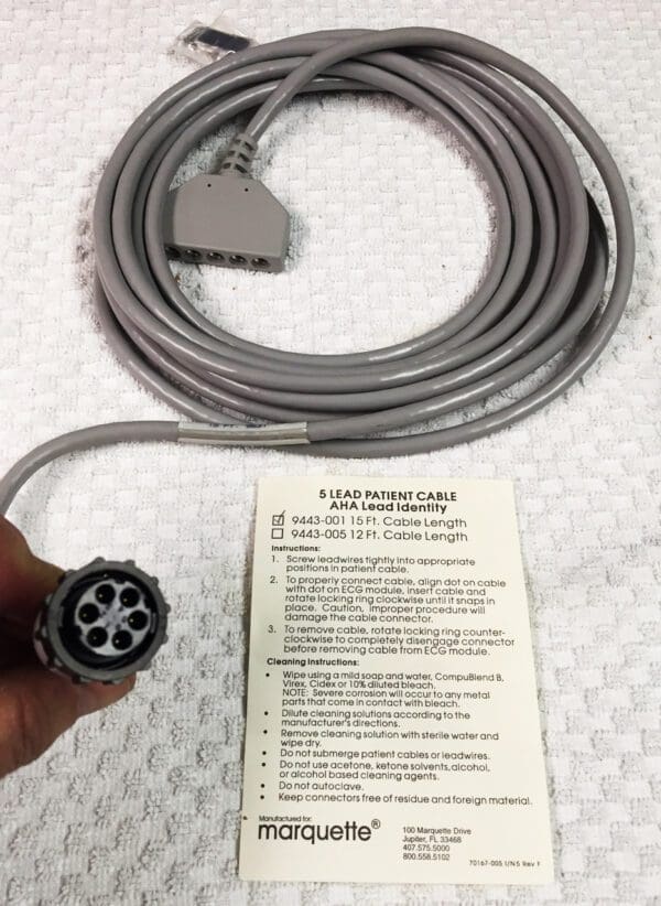 A person is holding a grey cable with a label on it.