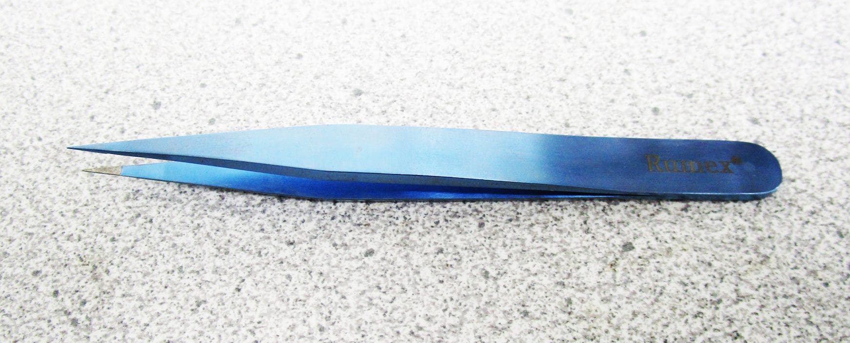 A blue metal tweezer sitting on the ground.