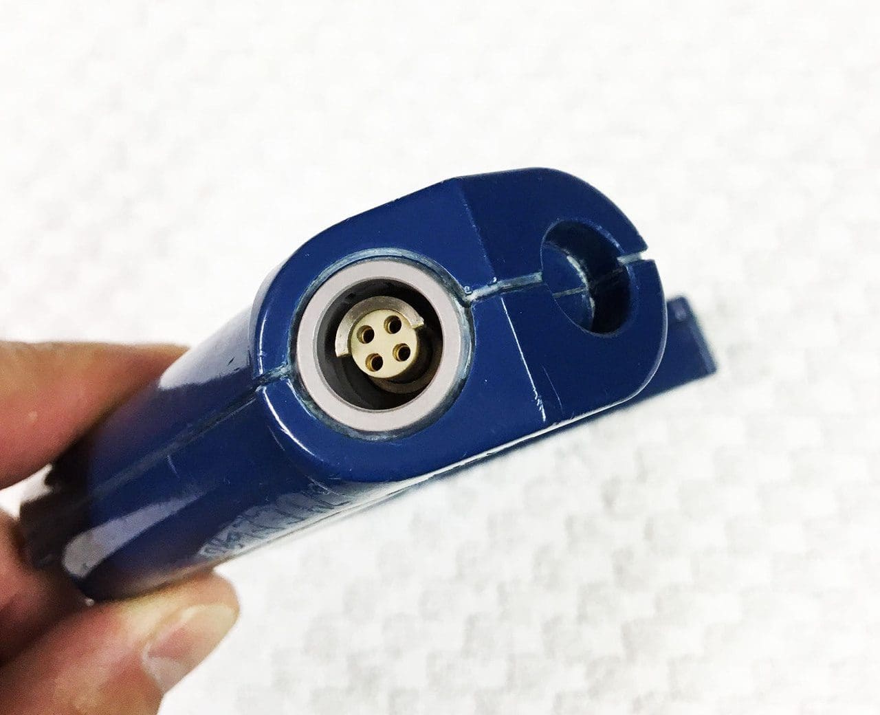A person holding a blue cigarette lighter with a small hole in it.