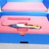 A pink box with a yellow and white electric hair iron in it.