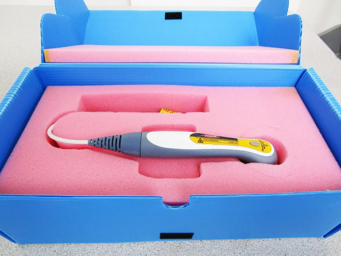 A pink box with a yellow and white electric hair iron in it.