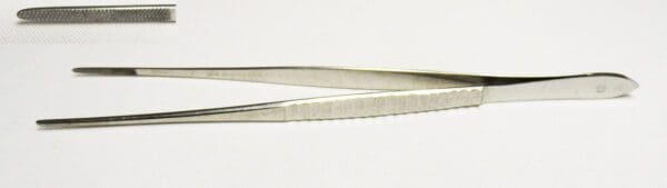 A pair of metal tweezers on a white surface.