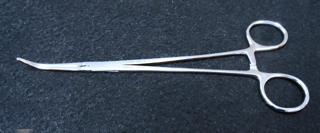 A pair of surgical scissors on a black surface.