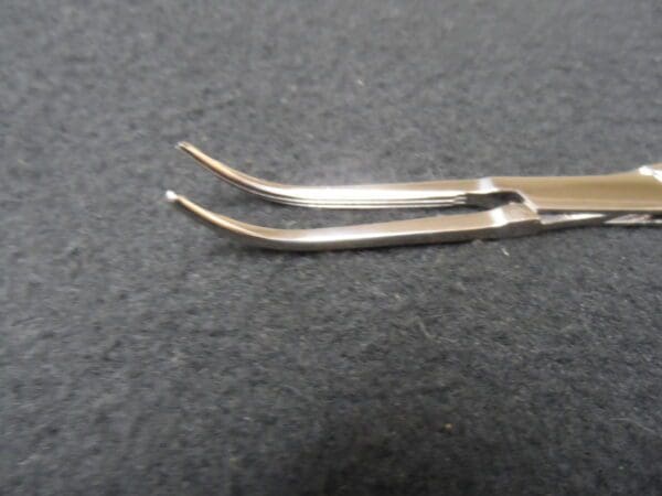 A pair of stainless steel tweezers on a black surface.